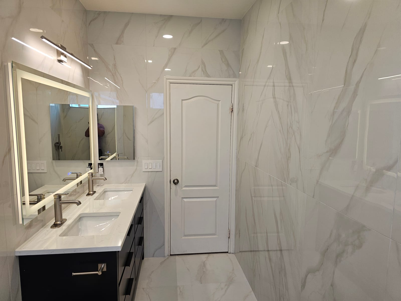 Master bathroom with Calacatta marble walls, floating double vanity, and backlit LED mirrors