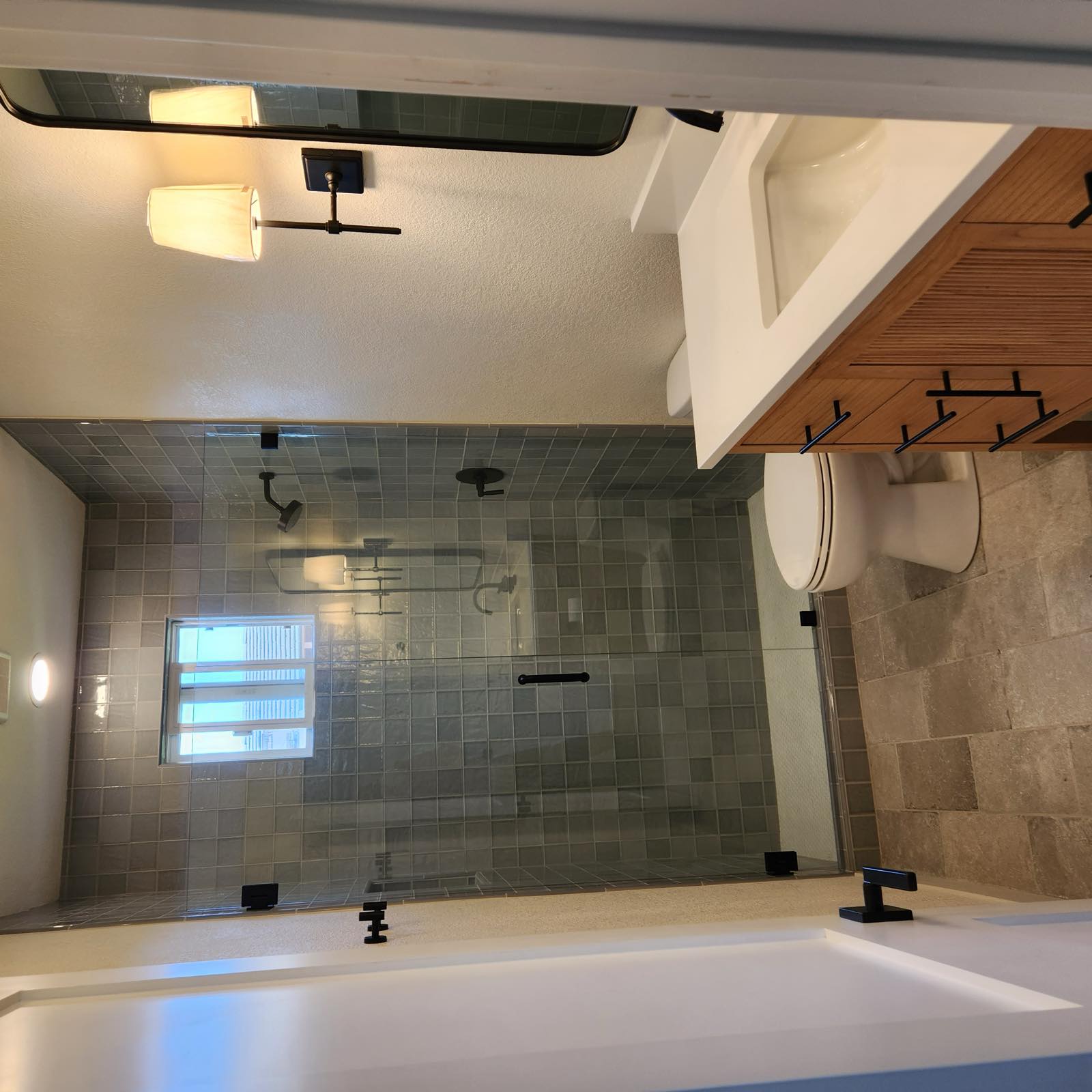 Guest bathroom with green square tile glass shower, travertine floor, and fluted wood vanity