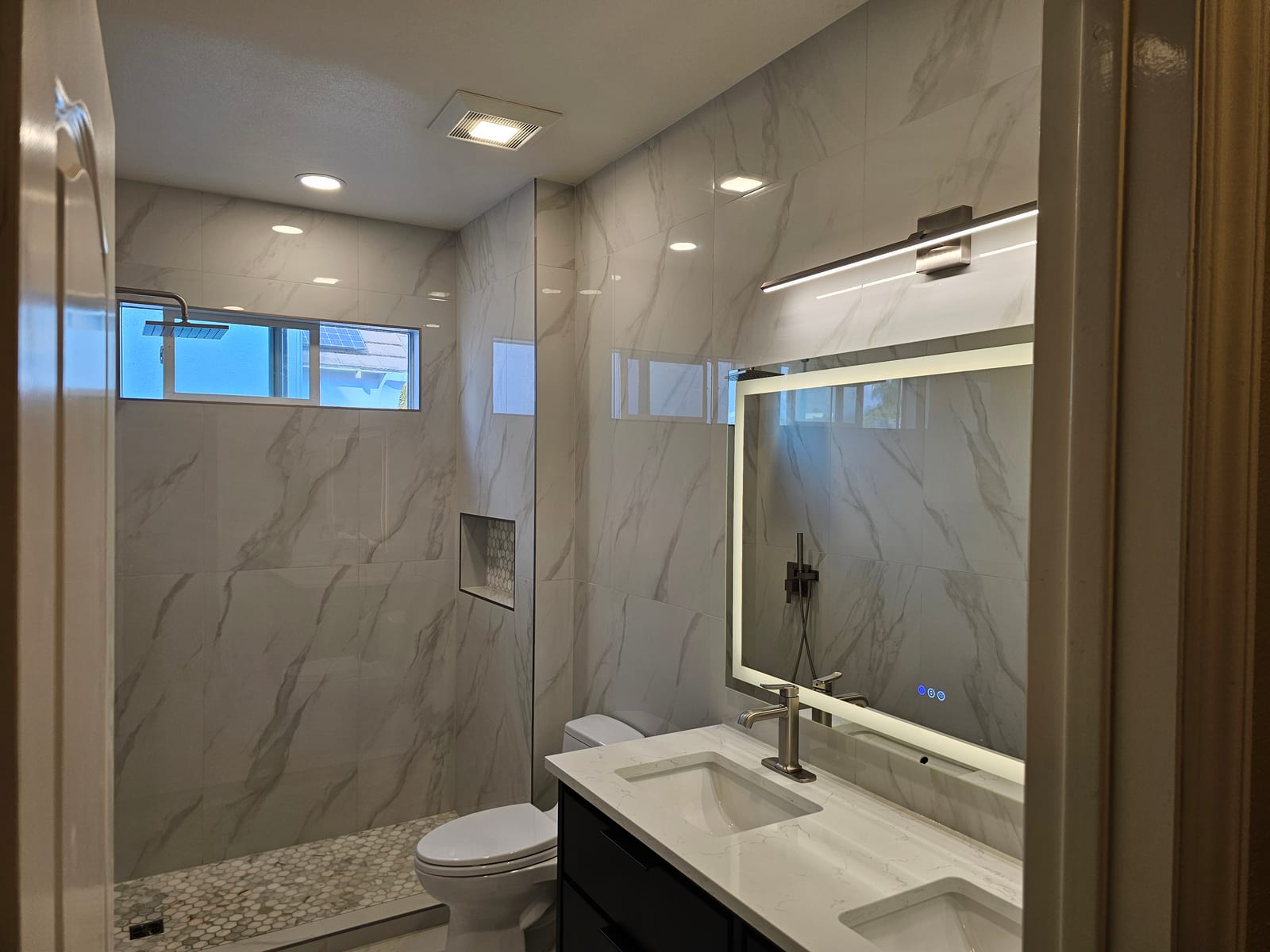 Marble walk-in shower with rainfall head, glass enclosure, and quartz vanity